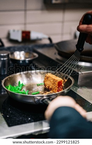 man chef cooking fried tuna fish and green bean in frying pan on kitchen