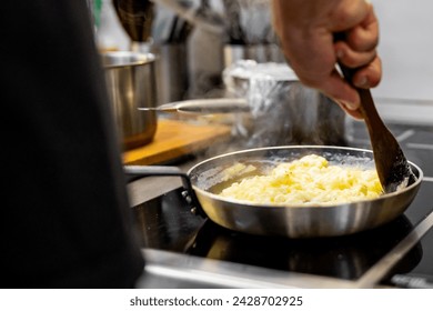 man chef cooking tasty scrambled eggs in frying pan on kitchen - Powered by Shutterstock