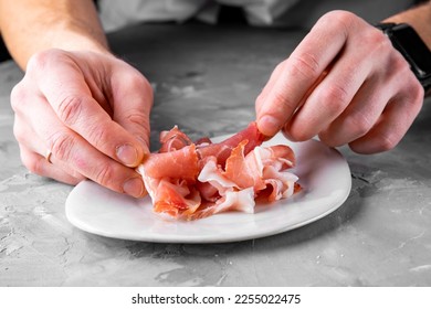 man chef hand takes Prosciutto crudo, parma ham - Shutterstock ID 2255022475