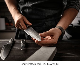 Man cheking a knife after using sharpen stone tool. Master sharpening knife on a grindstone - Powered by Shutterstock