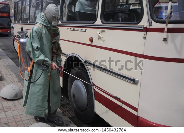 Man in a chemical radiation protection suit\
disinfects the surface of the bus during a press tour of the\
tourist route “The filming location of the Chernobyl mini-series in\
Kiev”, Kiev, July 12, 2019