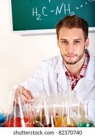 Man chemistry student with flask in classroom.