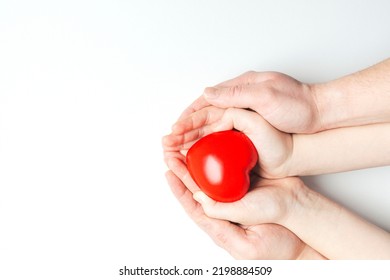 Man and child hands holding red heart on white background. Health care, love, organ donation and family insurance concept. 