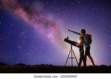 Man and child looking at stars through telescope. Family camping and hiking fun. Outdoor astronomy hobby. Parent and kid watch night sky with milky way. Boy observing planets and moon.  - Shutterstock ID 2253433947