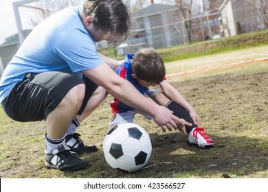 A Man With With Child Playing Football On Football Pitch