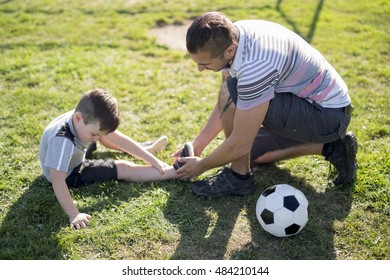 A Man With Child Playing Football Outside On Field