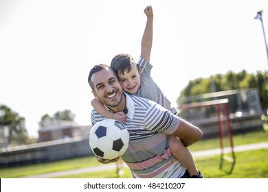 A man with child playing football outside on field - Powered by Shutterstock