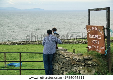 Man and a child standing near to a sign Board at the entrance of Prehistoric Dún Beag fort in Dingle Peninsula, Ireland