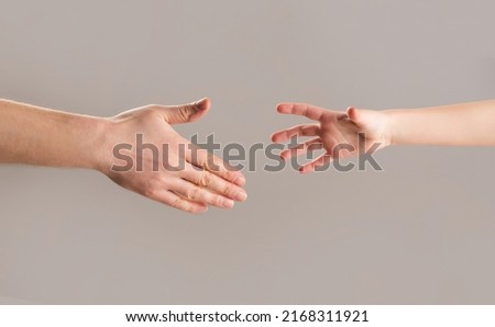Man and children hands reach toward each other. Child and father hands isolated on gray. Small child's hand reaches for the hand man. Helping hand concept, support. Helping hand outstretched.