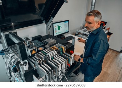 A man at a chip factory watches the work. Concept of technology and development of microchips. - Powered by Shutterstock