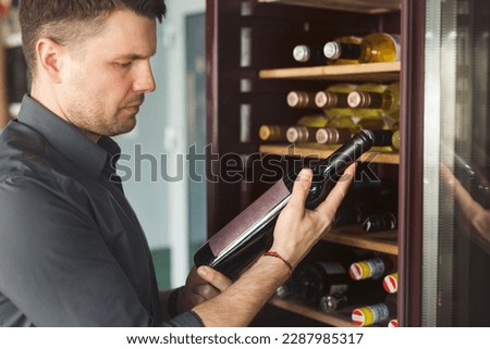 Man chooses bottle of aged vintage wine in winehouse.