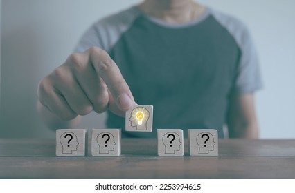Man chooses a wooden block with a person icon with a light bulb showing, selection concept people with ability to solve problems, wood block with different character icons has the idea and creativity.