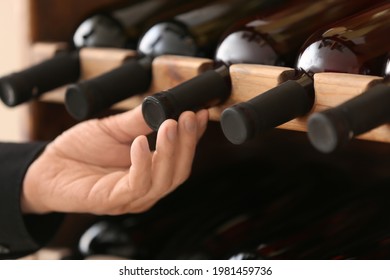 Man choosing bottle of wine in cellar, closeup - Powered by Shutterstock