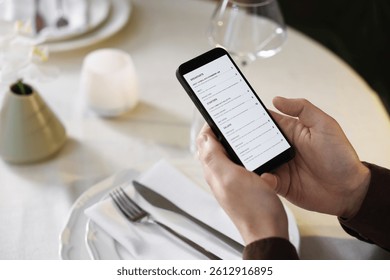 Hombre que elige el plato del menú en la mesa en el restaurante, en primer plano