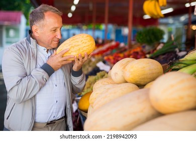 Man Choosing Fresh Melon In Market