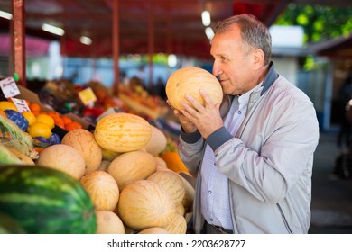 Man Choosing Fresh Melon In Market