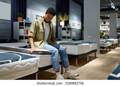 Man choosing mattress sitting on shop bed
