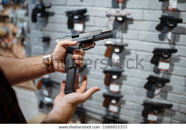 Man choosing new handgun\
in gun shop