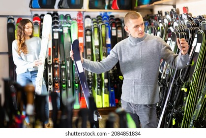 Man choosing new skis in store of sports equipment