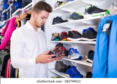 Man Choosing New Sneakers In Sports Store