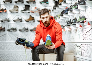 Man choosing trail shoes for hiking sitting in the fitting room of the modern sports shop - Powered by Shutterstock