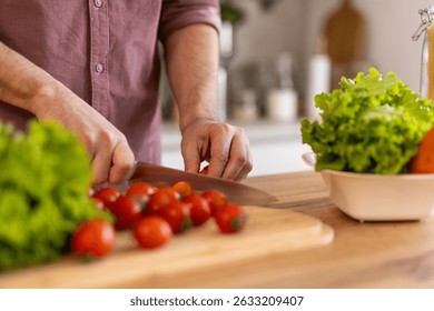 Man chopping vegetables in a kitchen, preparing ingredients for a meal. He is focused on the task, enjoying the process of cooking, with a relaxed and organized kitchen environment.