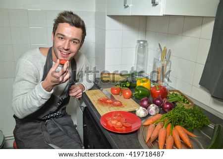 Man chopping vegetables in kitchen and using digital tablet