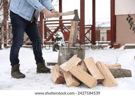Man chopping wood with axe outdoors on winter day, closeup