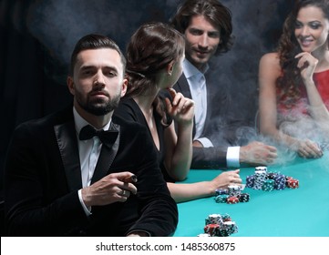 Man with cigar looking up from poker game in casino