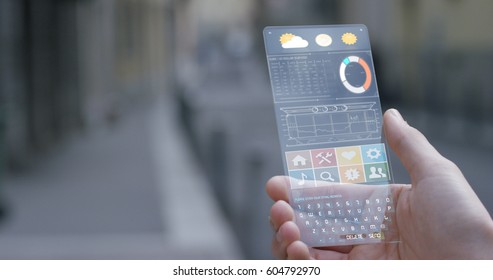 A man in the city, use the transparent phone with the latest technology with holography and watch the weather and the messages. Concept: technology, future and futuristic technology. - Shutterstock ID 604792970