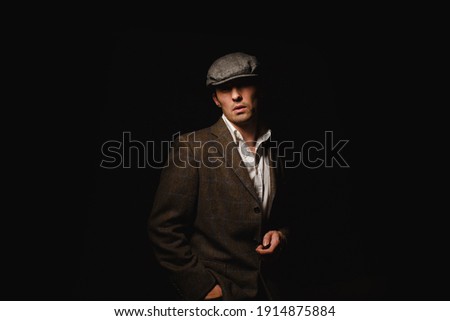 A man in a classic jacket and cap. 