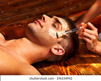 Man With Clay Facial Mask In Beauty Spa.