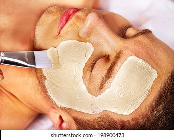 Man With Clay Facial Mask In Beauty Spa.