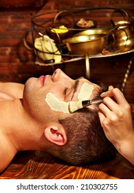 Man With Clay Facial Mask In Beauty Spa.