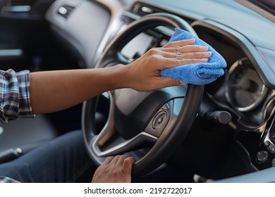 Man clean dust on the dashboard of his car with cloth.