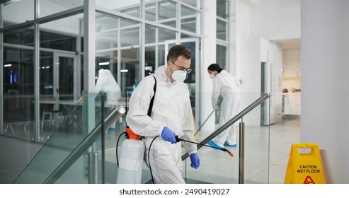 Man, cleaner and fumigation for hygiene, fresh and disinfectant for virus protection and maintenance. People, ppe suit and spray for bacteria, disease and prevention in office as team in pest control - Powered by Shutterstock