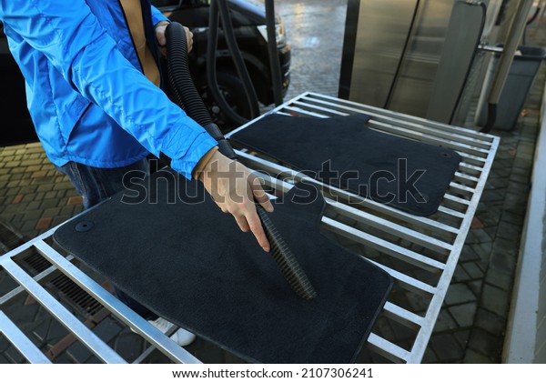 Man cleaning auto carpets with vacuum cleaner at\
self-service car wash,\
closeup
