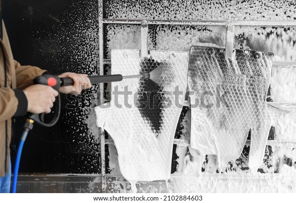 Man cleaning auto mats with high pressure\
water jet at self-service car wash,\
closeup