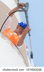 Man Cleaning A Balcony Wall Using A Pressure Washer