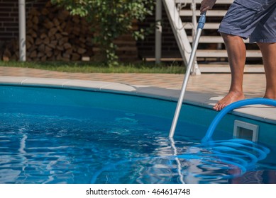Man cleaning blue swimming pool with vacuum cleaner, closeup 