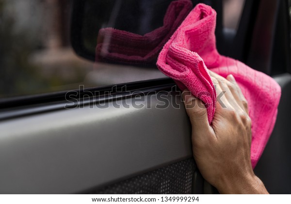 The man cleaning car with chemicals on pink\
microfiber cloth in the\
garden.