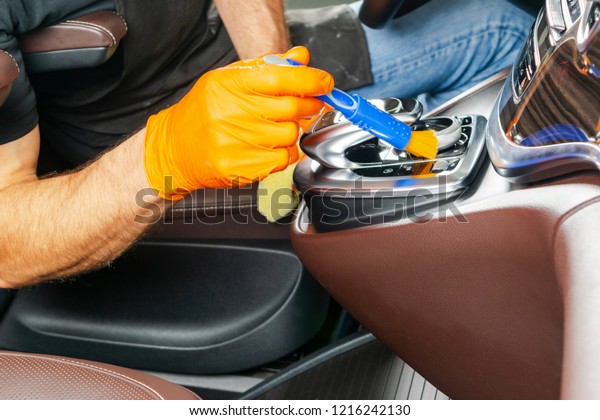 A man cleaning car with\
cloth and brush. Car detailing. Selective focus. Car detailing.\
Cleaning with brush. Worker cleaning. Brush and cleaning solution\
to clean.