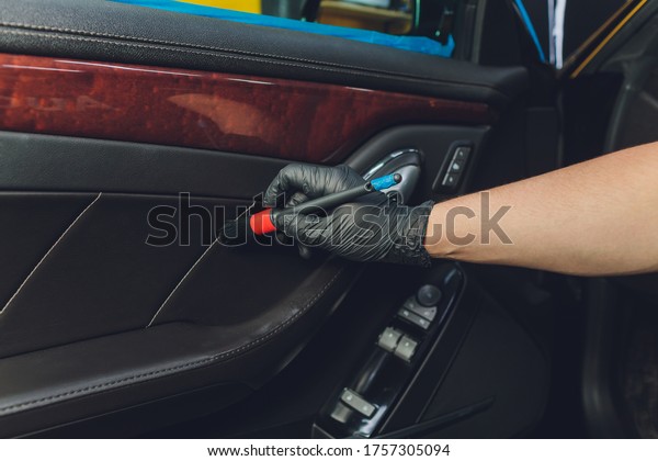 A man cleaning car with\
cloth and brush. Car detailing. Selective focus. Car detailing.\
Cleaning with brush. Worker cleaning. Brush and cleaning solution\
to clean.
