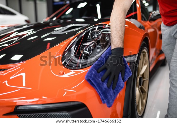 A man cleaning car with cloth, car\
detailing (or valeting) concept. Selective focus.\
