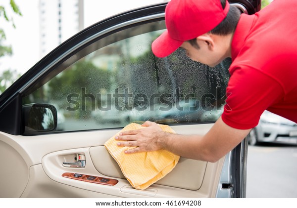 A man cleaning car door interior\
panel with microfiber cloth - auto cleaning service\
concept