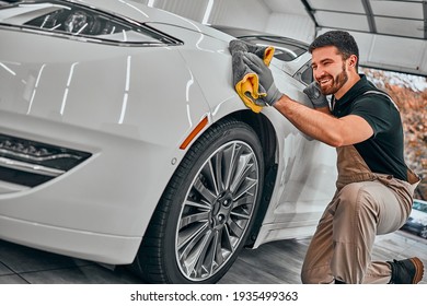 Man Cleaning Car And Drying Vehicle With Microfiber Cloth. Hand Wipe Down Paint Surface Of Shiny White Car After Polishing And Ceramic Coating. Car Detailing And Car Wash Concept. Selective Fiocus.