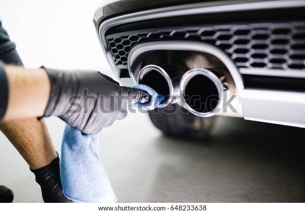 A man cleaning car\
exhaust with microfiber cloth, car detailing (or valeting) concept.\
Selective focus. 