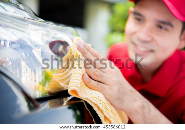 A man cleaning car headlight - car detailing and\
valeting concept