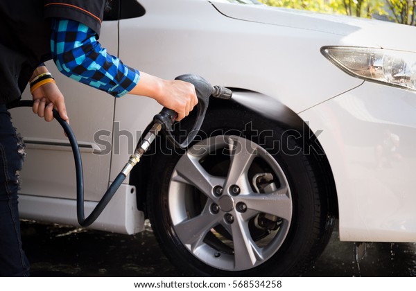 Man cleaning a car with high pressure cleaning in\
car wash