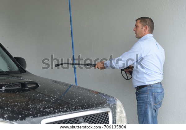 man cleaning a\
car with high pressure\
water